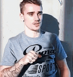 a man wearing a gray t-shirt with the word sport on it is holding a microphone .