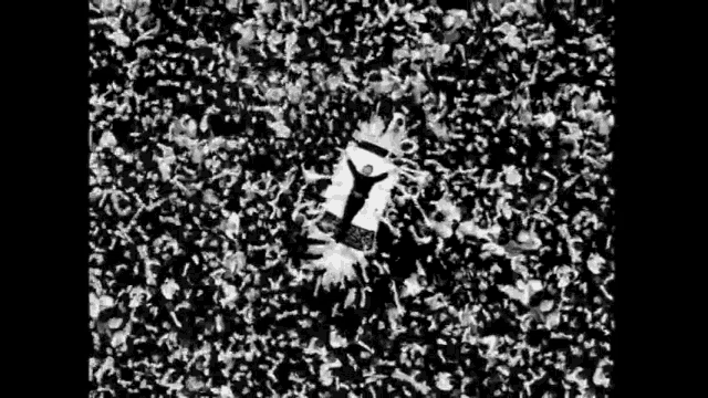 a black and white photo of a crowd of people at a concert with a person laying on the ground .