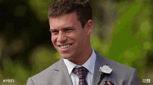 a man in a suit and tie smiles with # mafs written on the bottom
