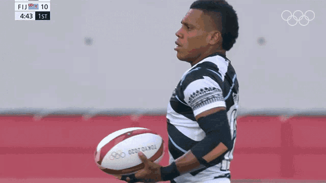 a rugby player holds a tokyo 2020 ball