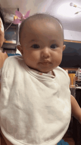 a baby wearing a bib is being held by a person