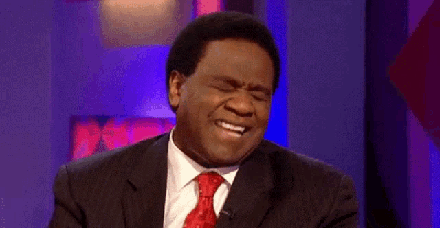 a man in a suit and tie is making a funny face while talking on a television show .