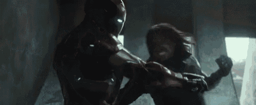 a man in a red suit is fighting another man in a black suit in a dark room .