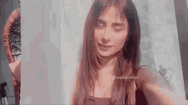 a woman with long hair is taking a selfie in front of a wall .