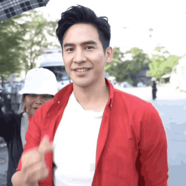 a man in a red shirt is giving a thumbs up sign
