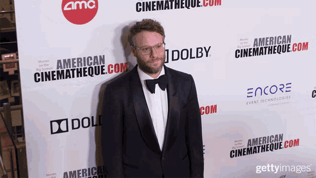 a man in a tuxedo is standing in front of a wall that says dolby