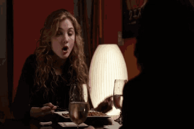 a woman sitting at a table with a plate of food and a glass of water