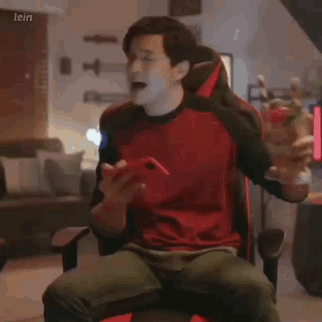 a man in a red shirt is sitting in a chair holding a milkshake with straws