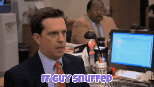 a man sitting in front of a computer with the words " it guy snuffed " above him