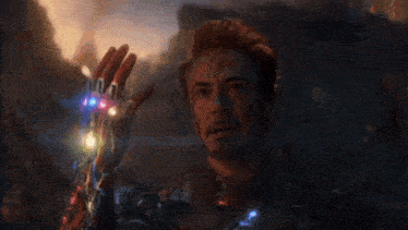 iron man is holding up his hand with a bunch of infinity stones on it .