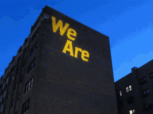 a large brick building has the words we are projected on it