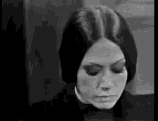 a black and white photo of a woman with long hair and a scarf around her head .