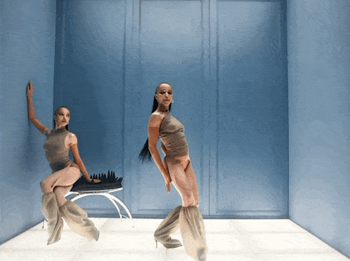 two women are dancing in a blue room