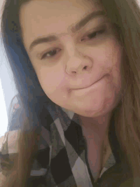 a young woman with a nose ring is making a face .