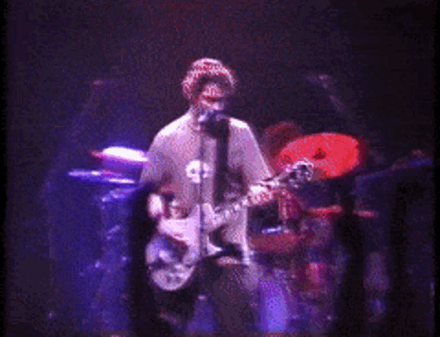 a man singing into a microphone while playing a guitar on stage