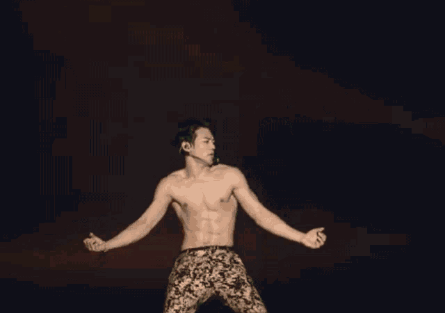 a shirtless man with a microphone on his neck is dancing