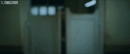 a blurry picture of a person standing in a doorway with xtoms written in the corner