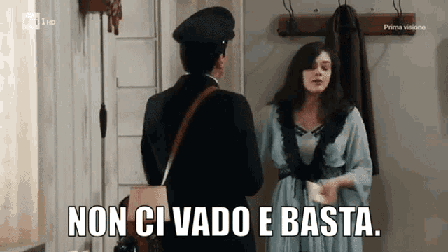 a woman in a blue dress is talking to a man in a black hat with the caption non ci vado e basta