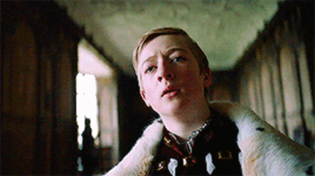 a young boy wearing a fur coat in a dark room