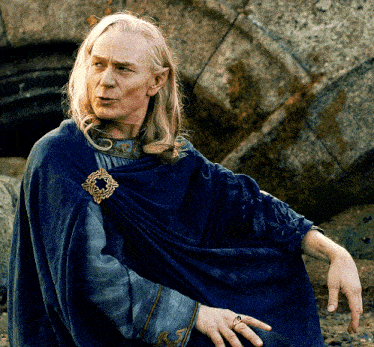 a man wearing a blue cape with a brooch on his shoulder