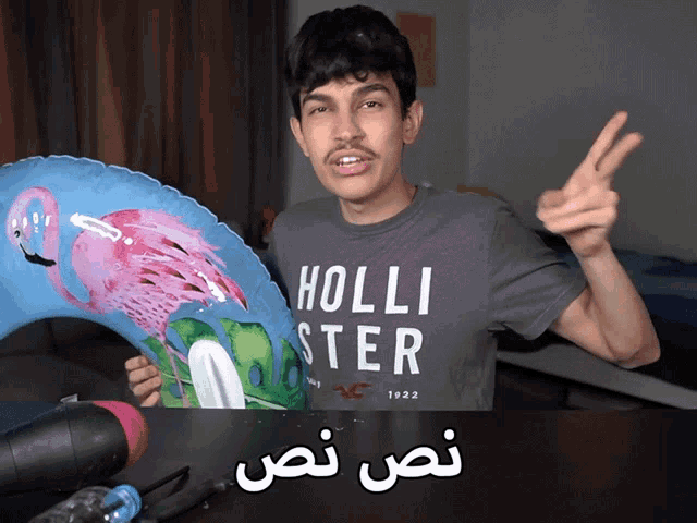 a man wearing a hollister shirt holds a flamingo shaped balloon