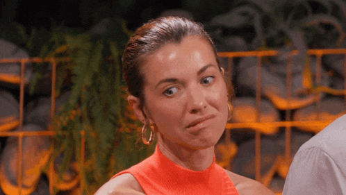 a woman in an orange top is making a face