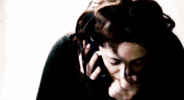 a woman in a black sweater is crying while talking on a cell phone