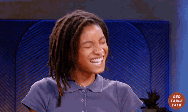 a woman with dreadlocks is laughing in front of a red table talk logo