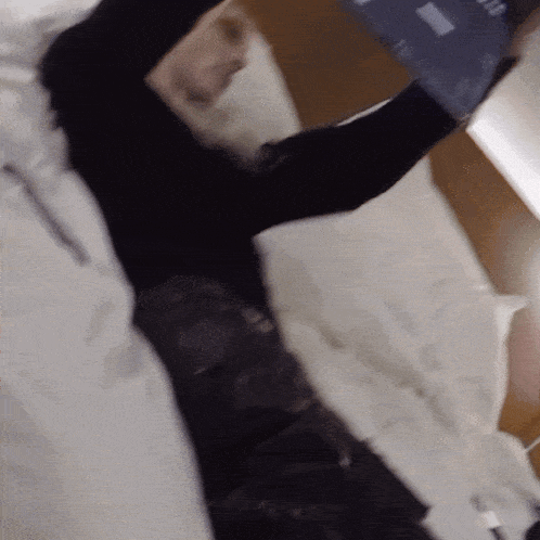 a blurry picture of a person laying on a bed with a tablet in their hand