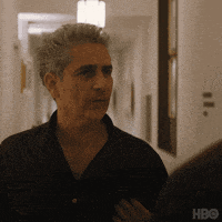 a man in a black shirt is standing in a hallway looking at another man .
