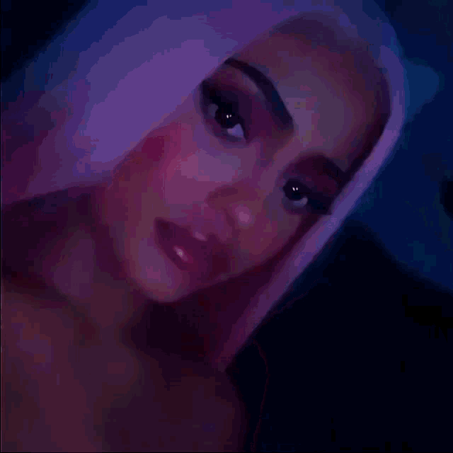 a close up of a woman 's face with pink hair and pink nails .