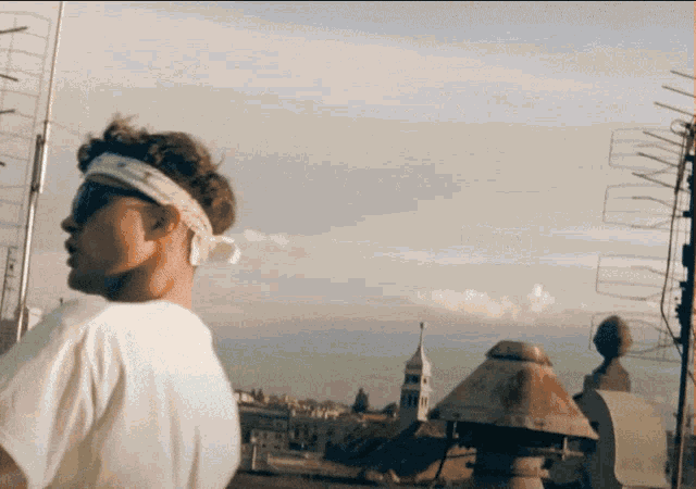 a man wearing sunglasses and a headband stands on a rooftop