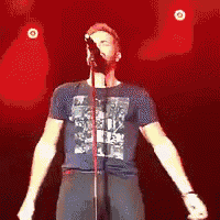 a man in a blue shirt is singing into a microphone .