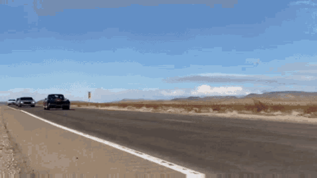 a row of cars are driving down a road in the desert