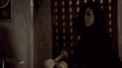 a woman is standing in front of a laptop computer holding a bat in her hand .
