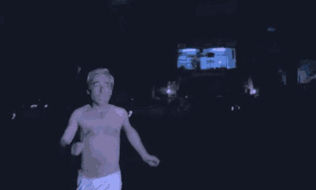 a man without a shirt is running in a dark room