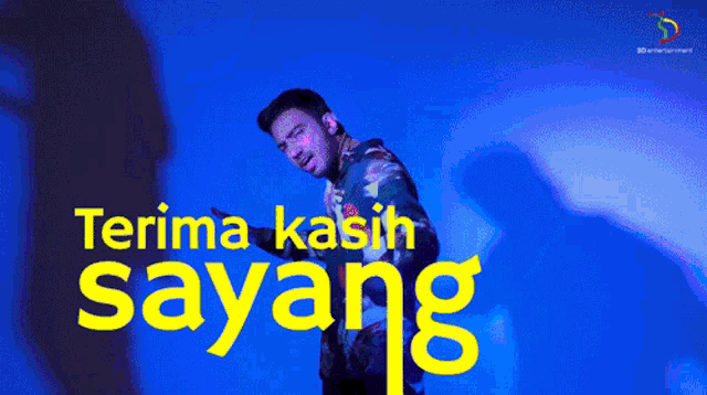 a man stands in front of a blue background with the words terima kasih sayang written in yellow