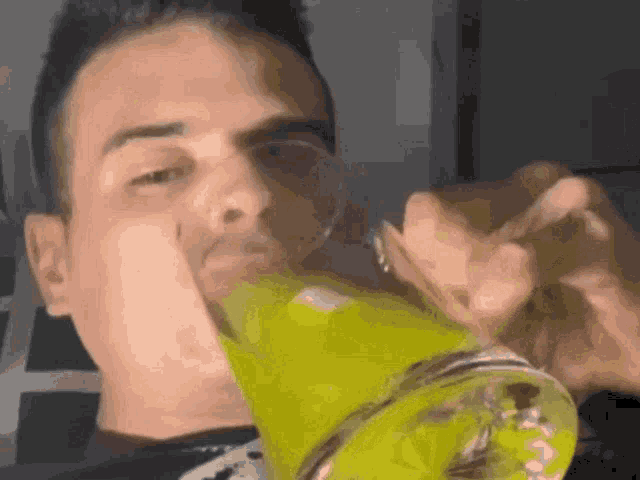 a man is drinking a glass of yellow liquid