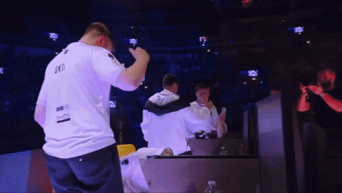 a man in a white shirt that says ' lks ' on the back stands next to another man
