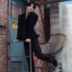 a woman in a black suit is standing on a set of stairs in front of a door that has a caution sign on it