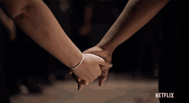 two people holding hands with the netflix logo in the corner