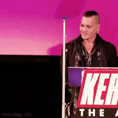 a man stands behind a podium with a sign that says ' ken ' on it