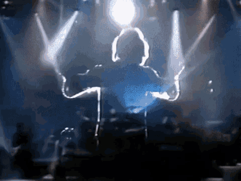 a silhouette of a man playing a guitar in front of a microphone on a stage