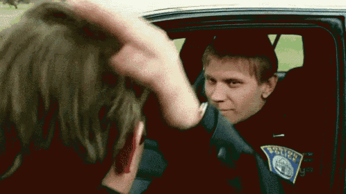 a police officer is putting his hand on another police officer 's head .