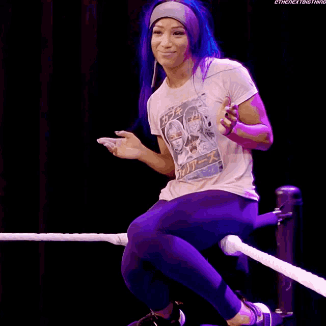 a woman with blue hair is sitting in a wrestling ring saying bayley come here