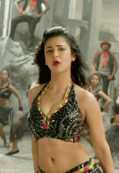 a woman in a crop top is dancing in front of a group of people