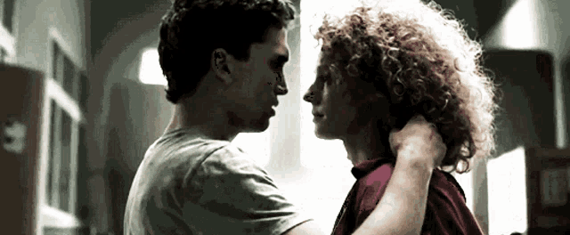 a man and a woman are looking into each other 's eyes and the woman has curly hair