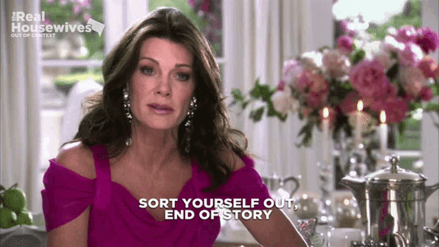 a woman in a purple dress is sitting at a table and says sort yourself out end of story