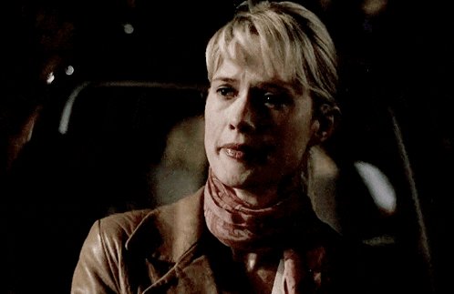 a woman wearing a scarf and a leather jacket looks down