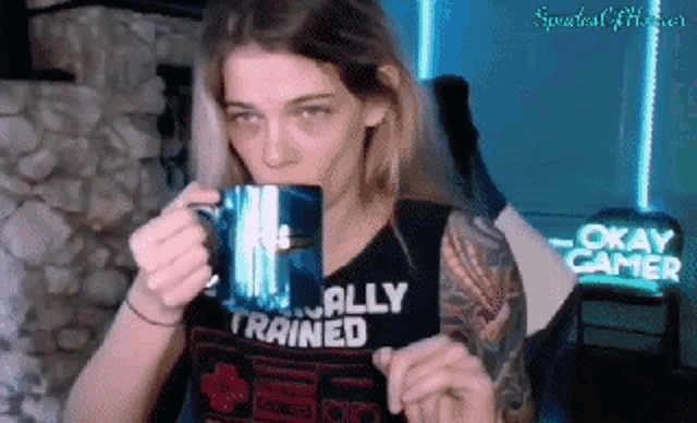 a woman is drinking from a mug that says okay gamer